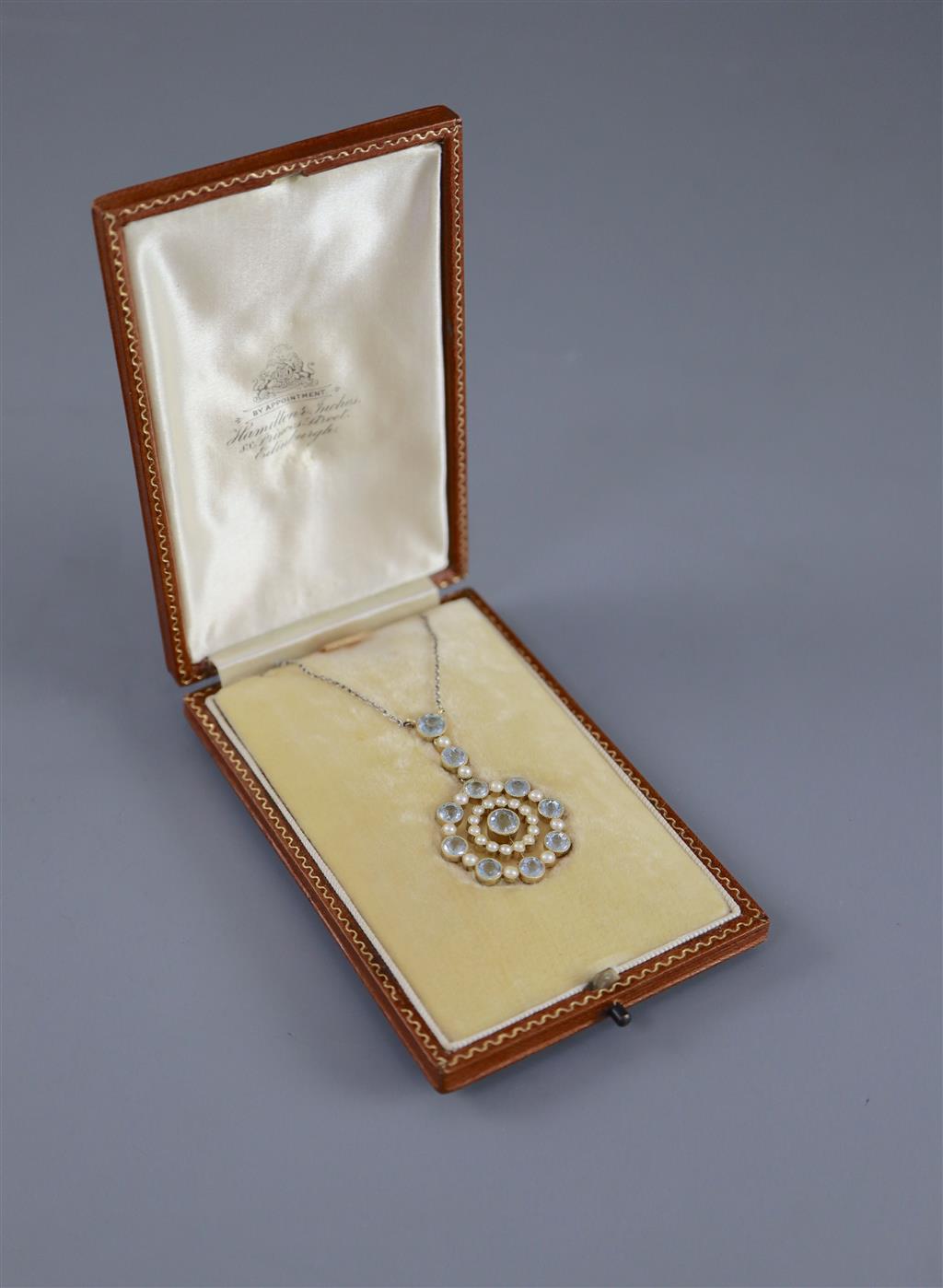 An Edwardian 15ct gold, aquamarine and seed pearl set circular drop pendant necklace,